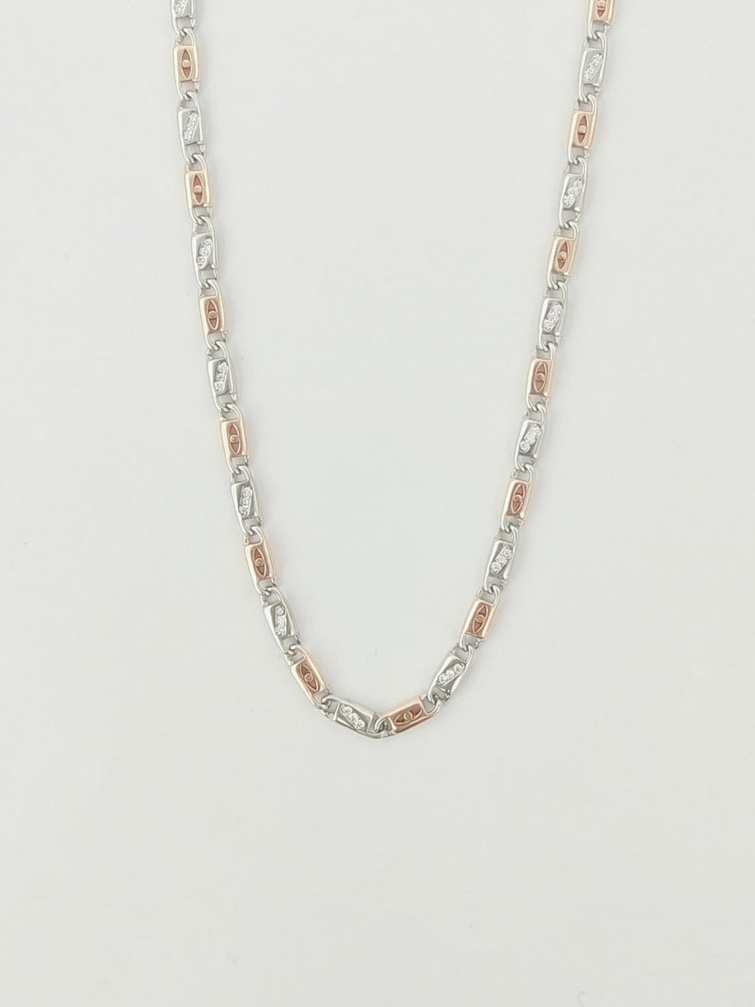 Silver and rose gold chain necklace on a light gray background