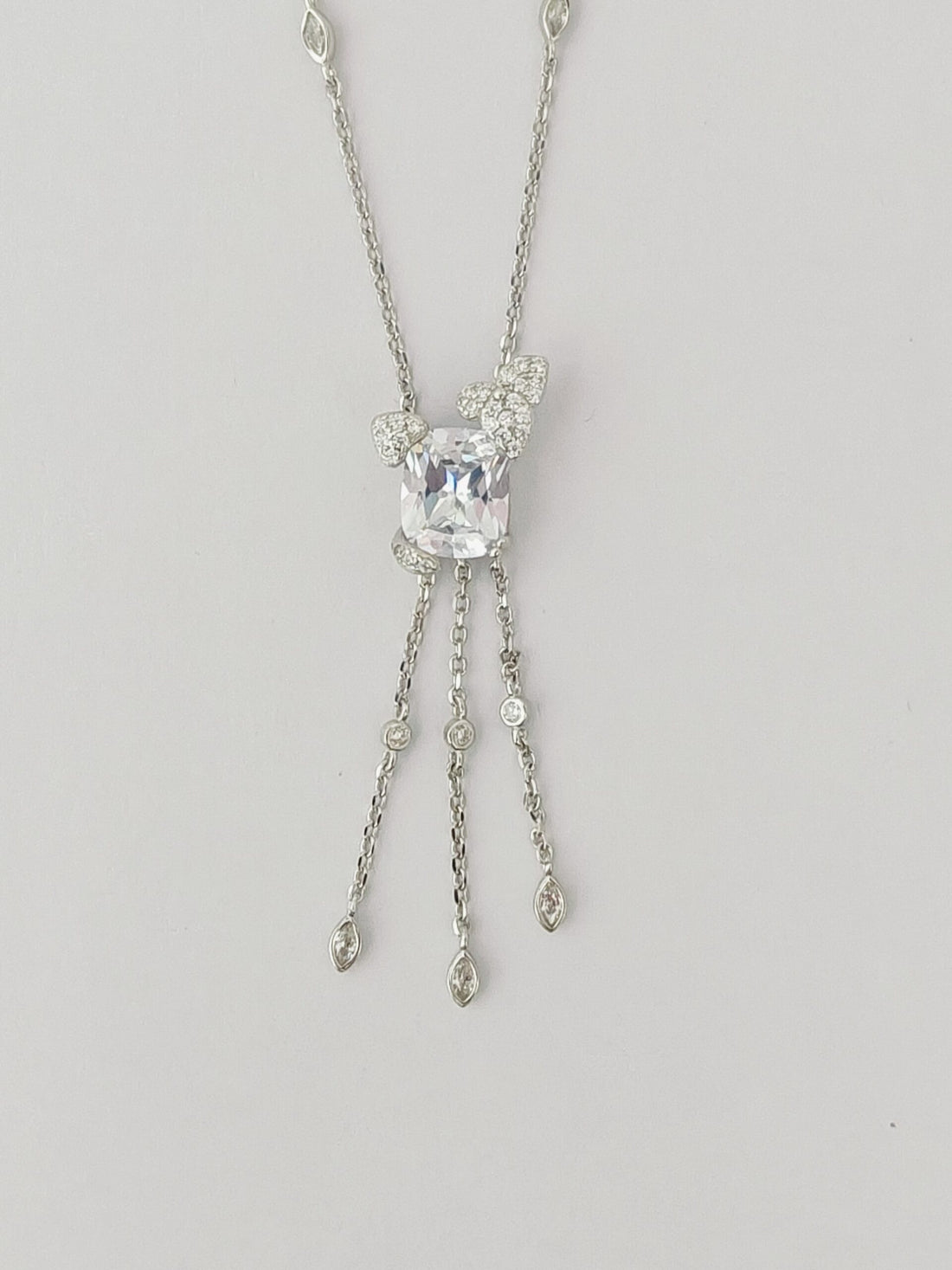 Silver necklace with a central gemstone on a light gray background