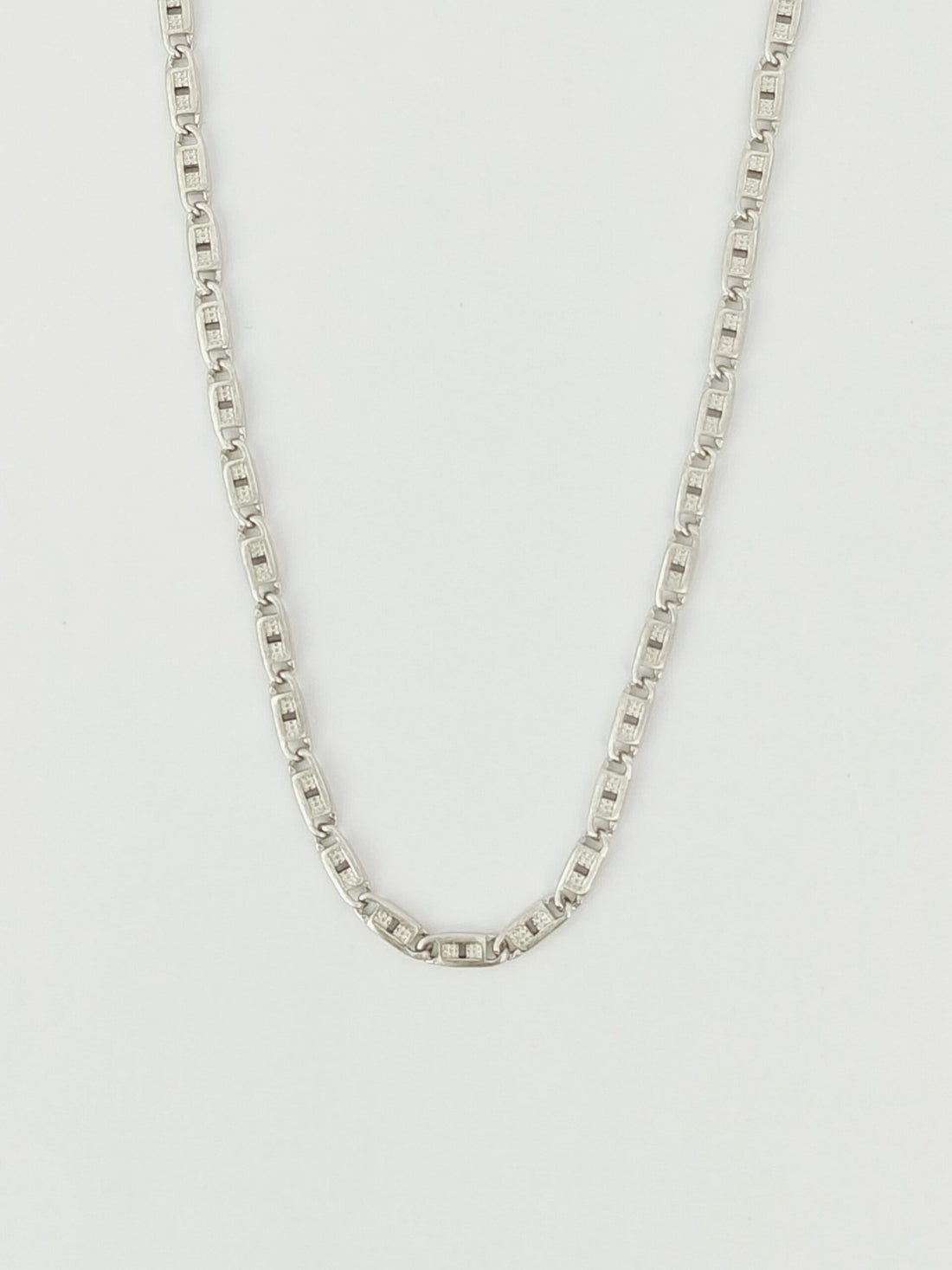 Silver chain necklace on a light gray background