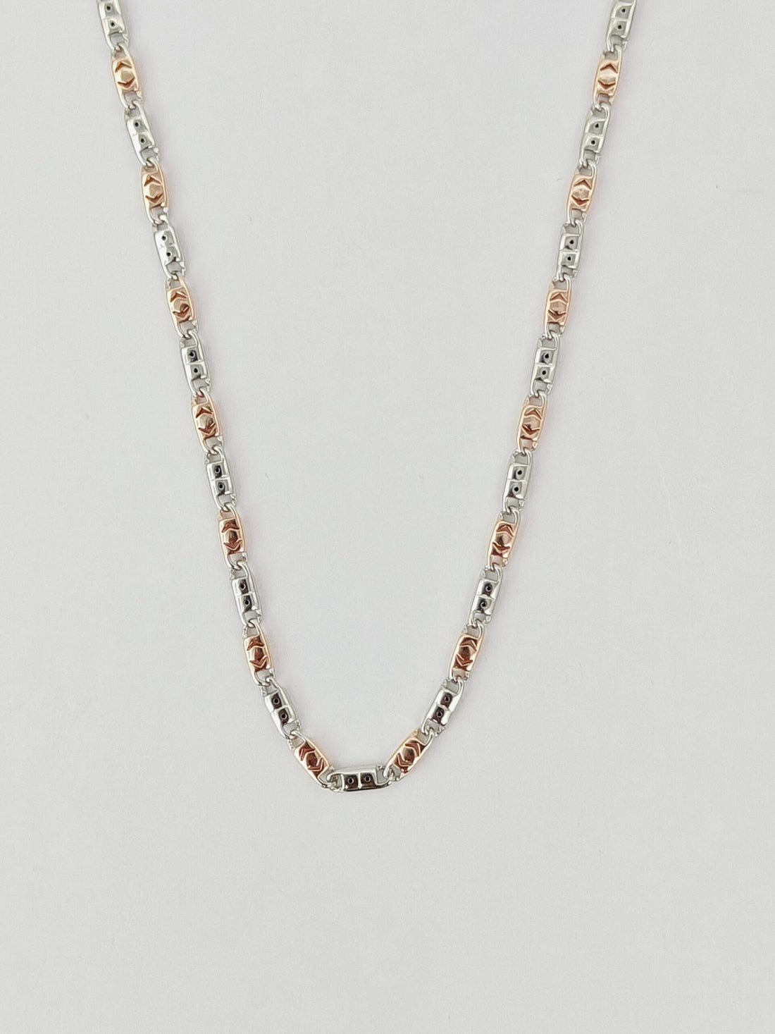 Silver and rose gold chain necklace on a light gray background