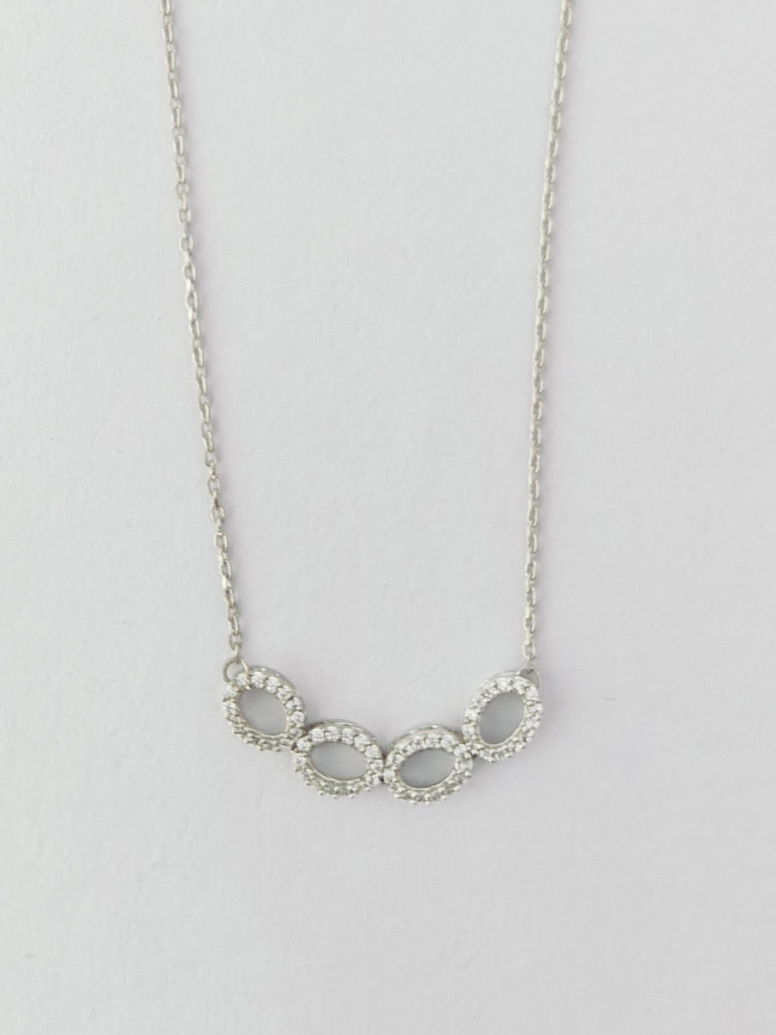 Silver necklace with interlocking rings on a light gray background