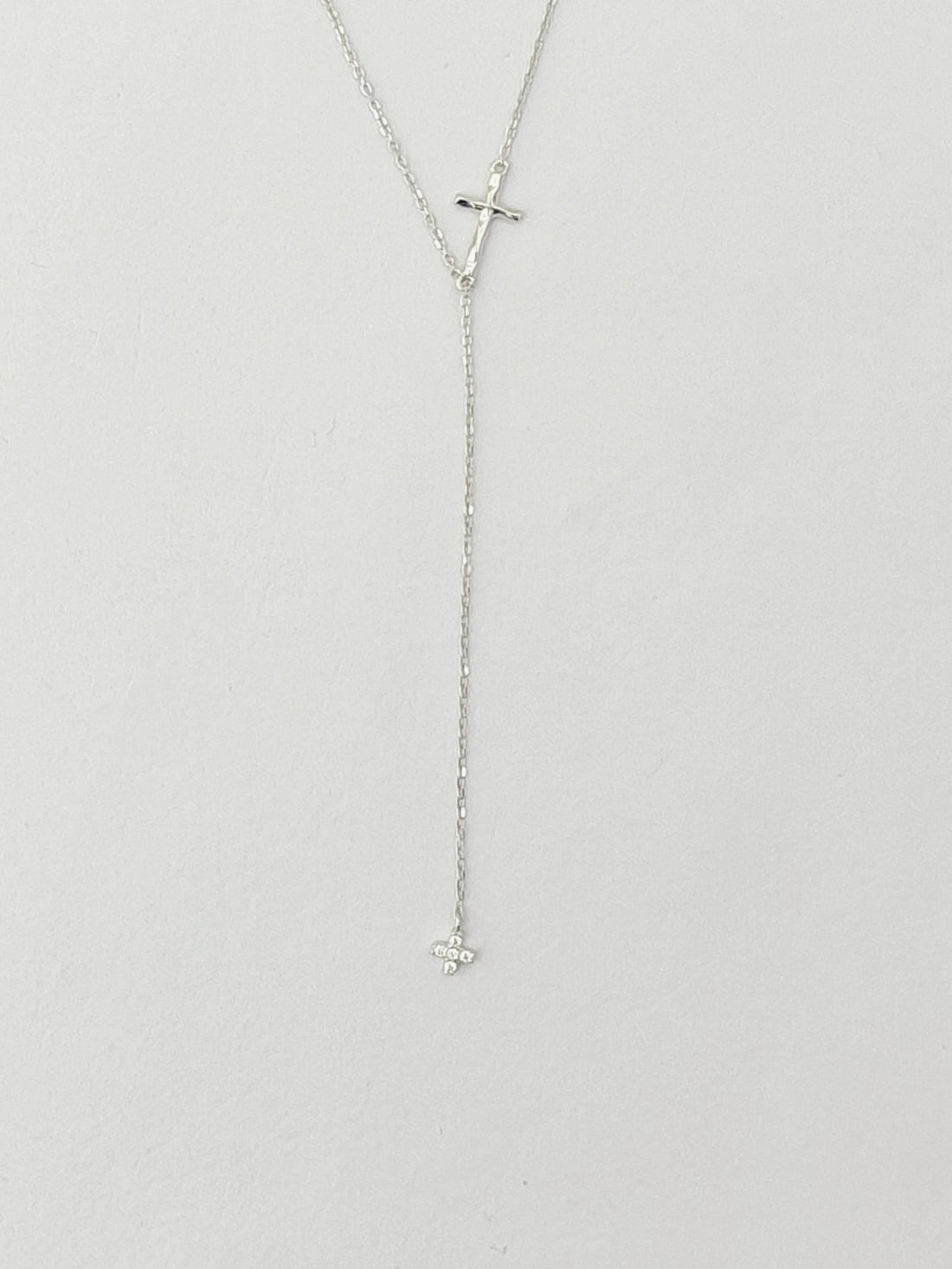 Silver necklace with a cross pendant on a light gray background