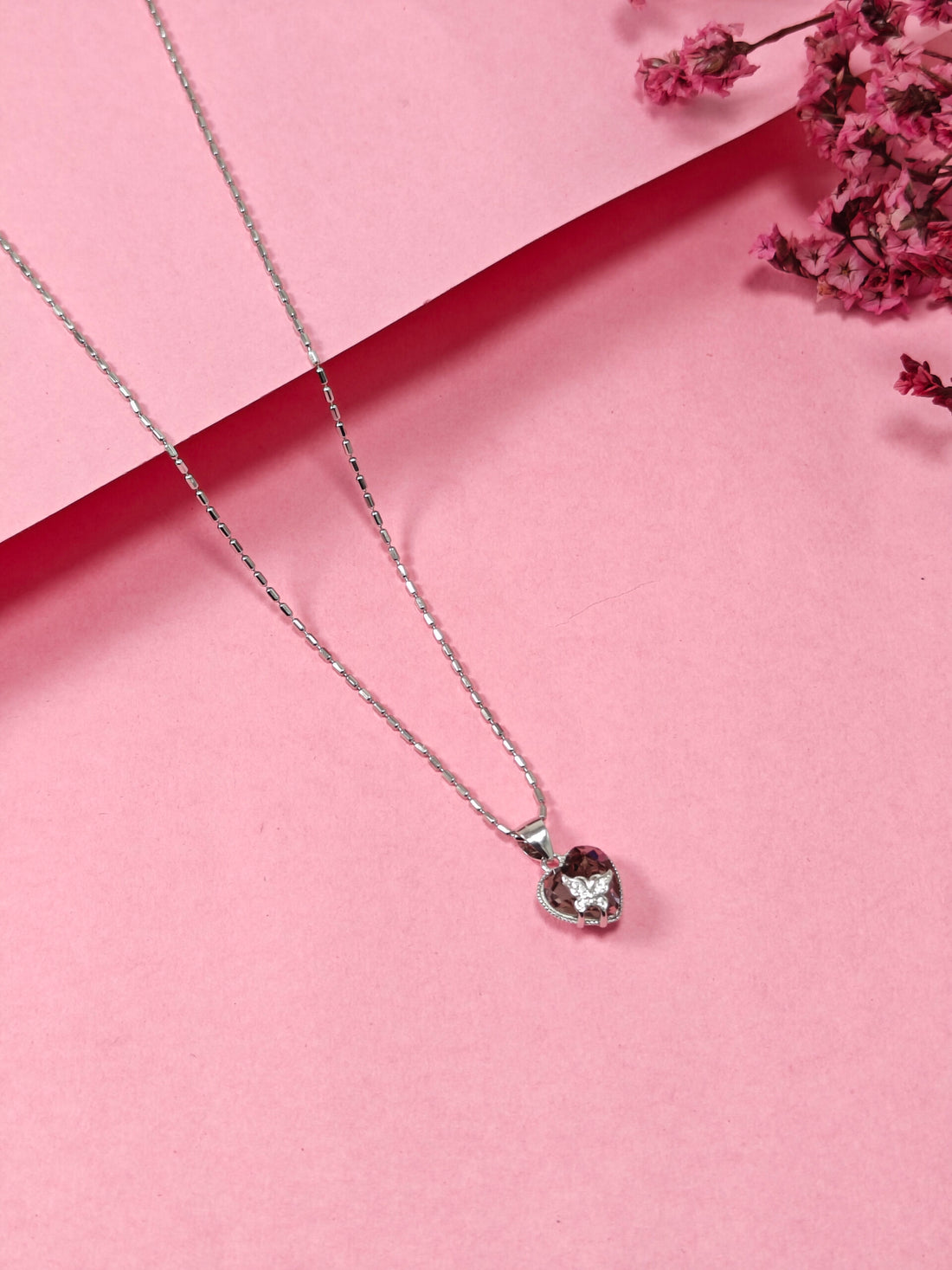 Necklace with a heart-shaped pendant on a pink background