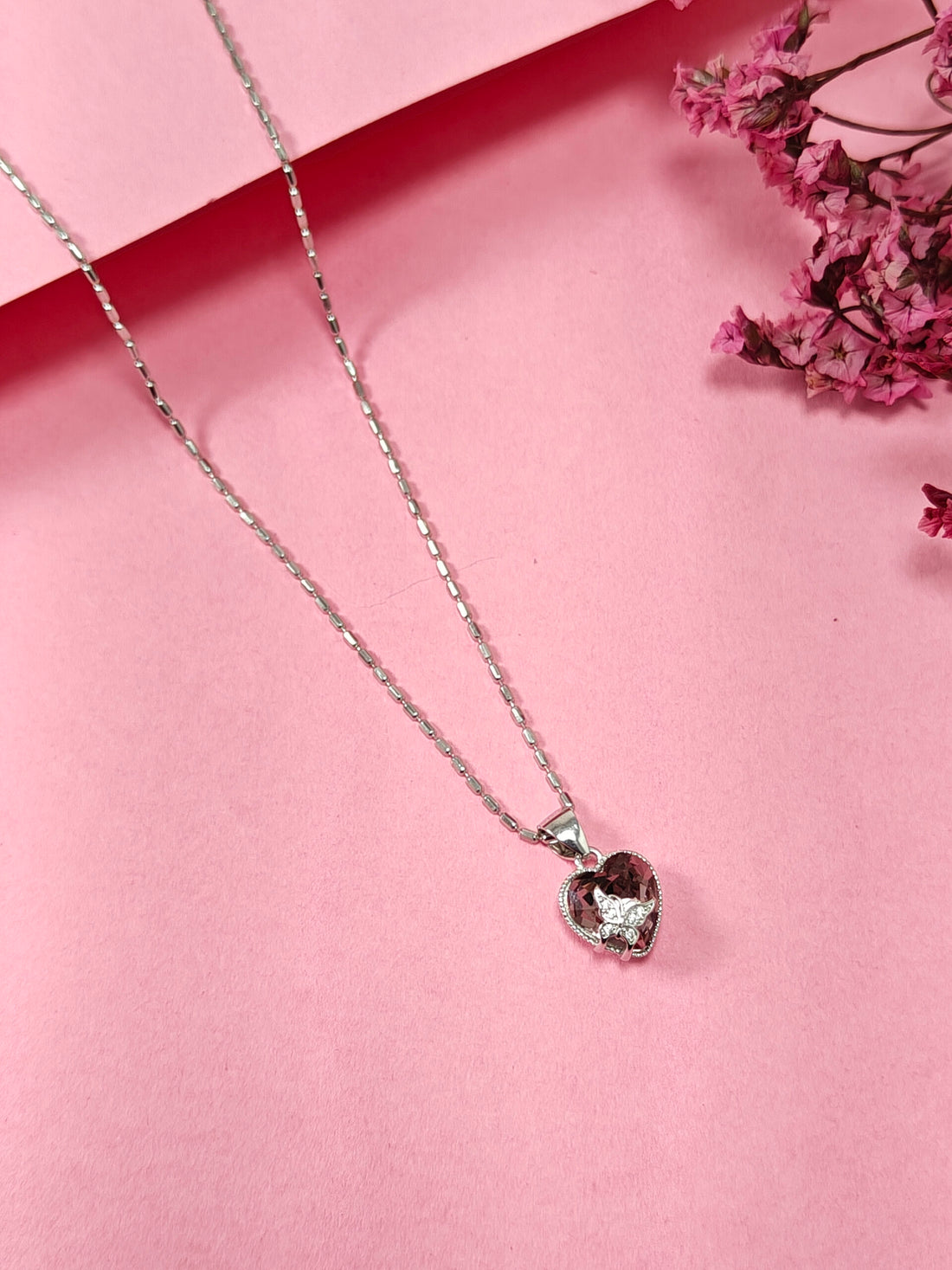 Necklace with a heart-shaped pendant on a pink background