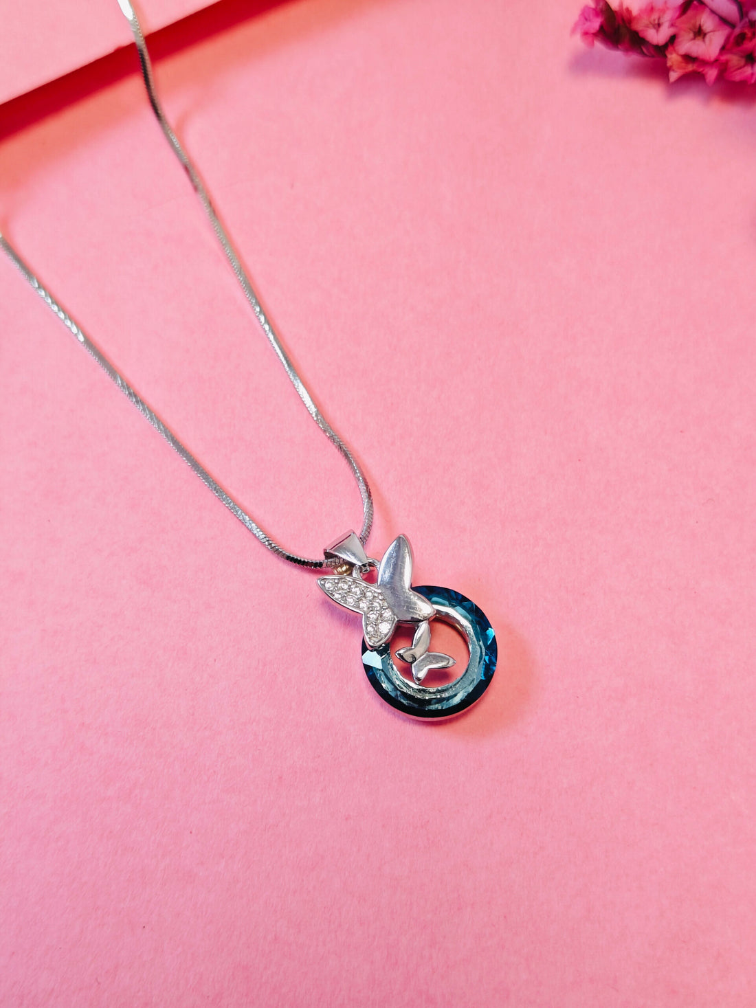 Silver necklace with a unique pendant on a pink background