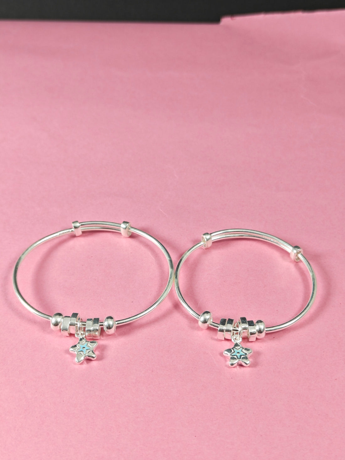 Silver hoop earrings with star-shaped charms on a pink background