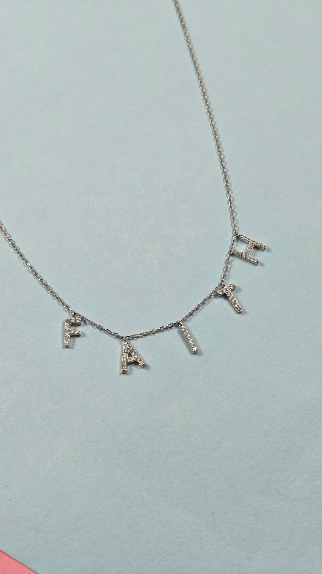 Necklace with 'FAIRE' pendant on a light gray background