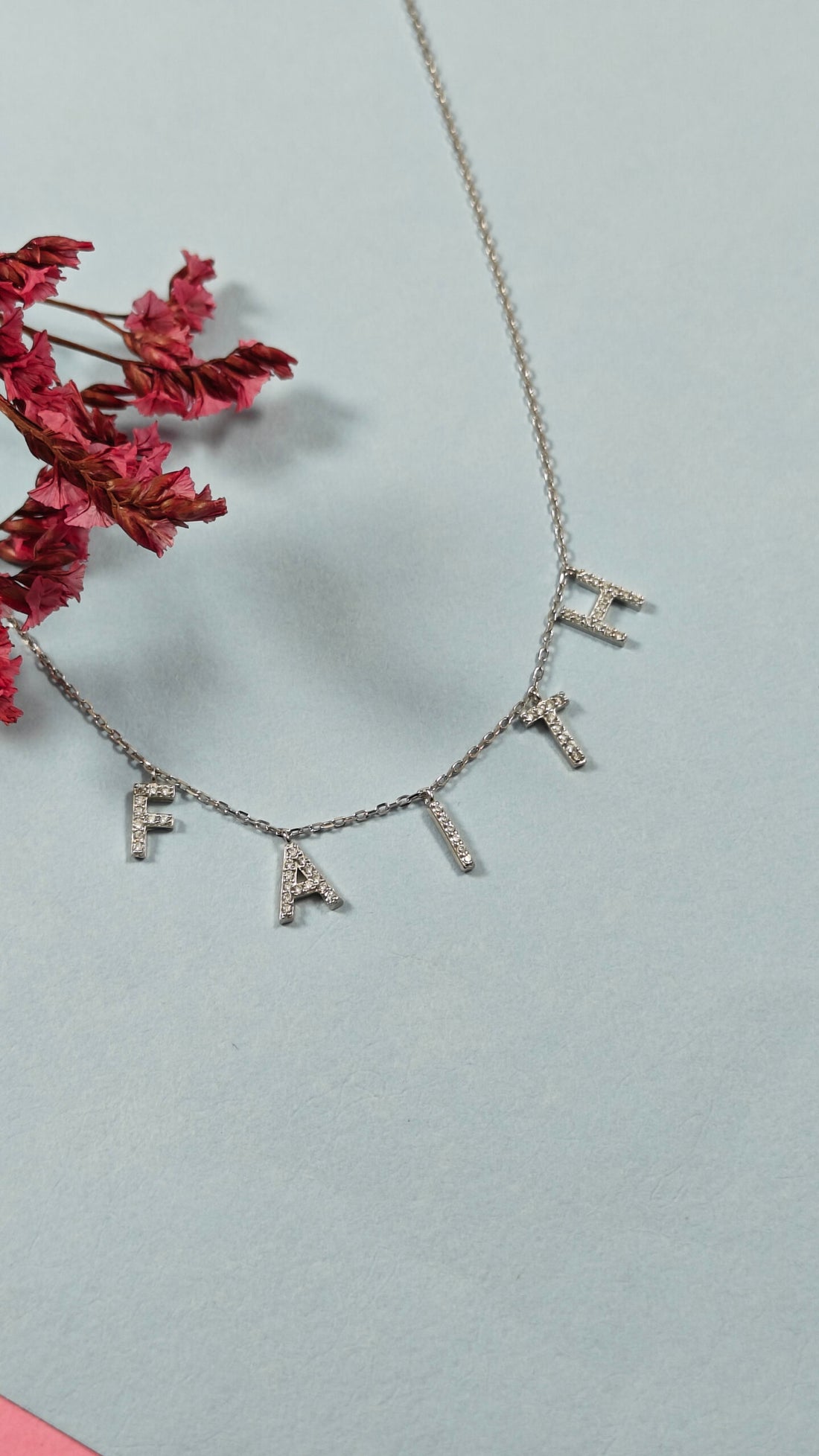 Necklace with diamond-studded letters on a light blue background