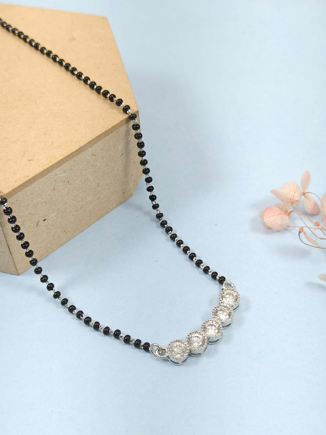 Necklace with black beads and silver clasp on a light blue background