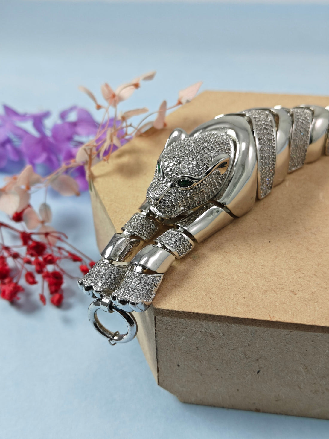 Silver panther bracelet on a textured surface with decorative elements