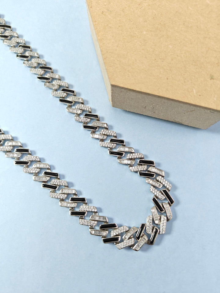 Silver chain necklace on a light blue surface with a beige box in the background