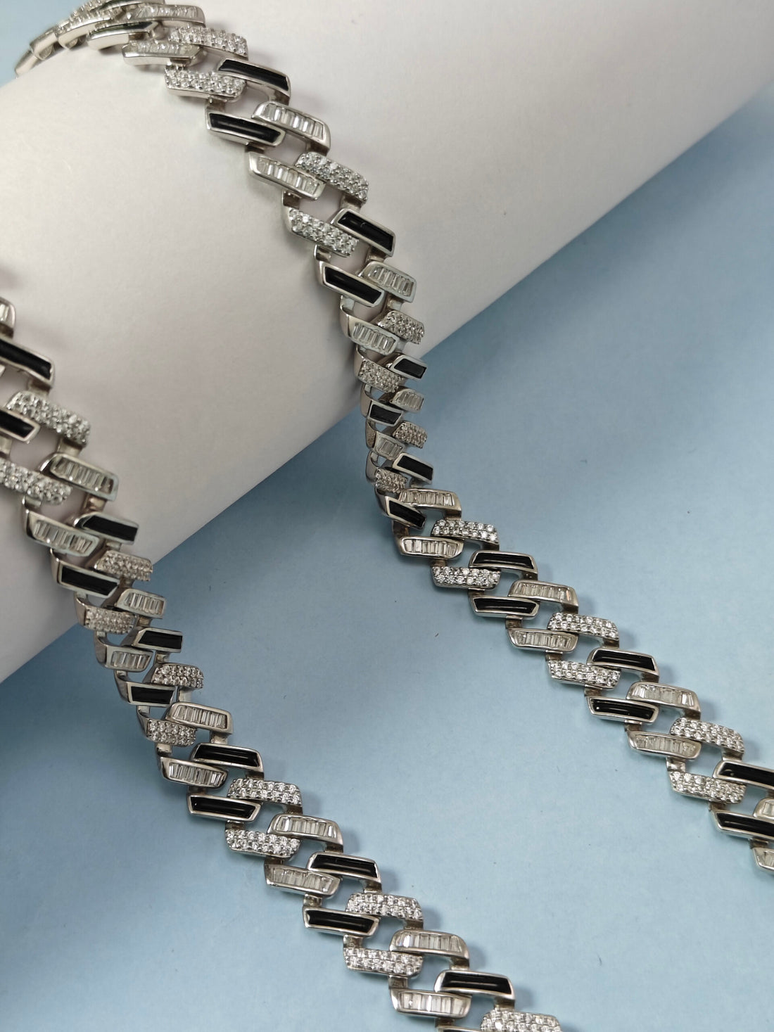 Silver necklace with black accents on a light blue background