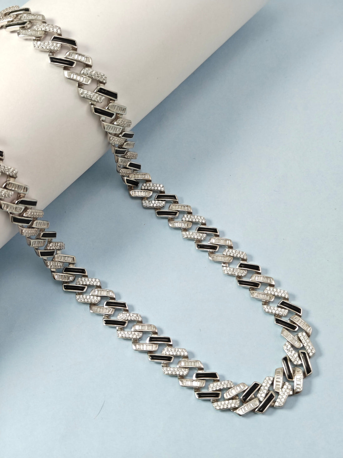 Silver chain necklace on a light blue background