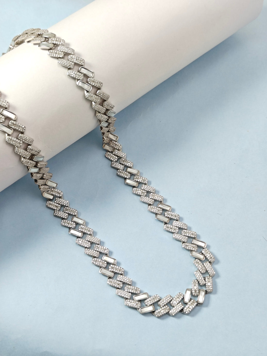 Silver chain necklace on a light blue background