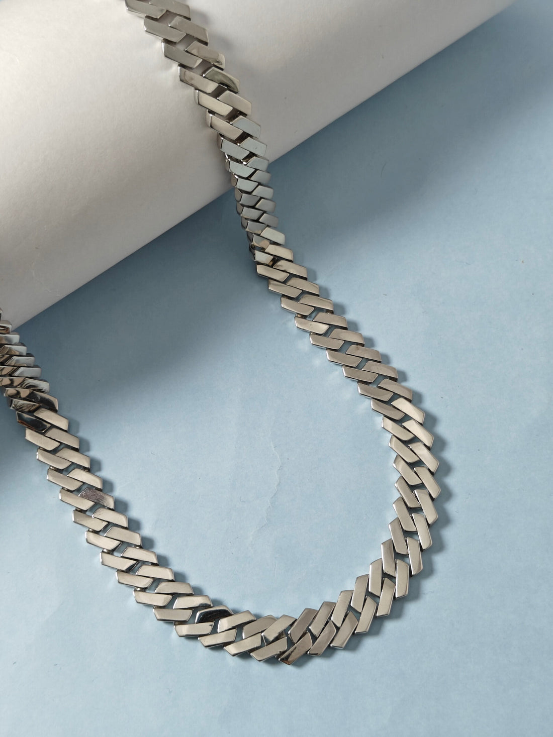 Silver chain necklace on a light blue background