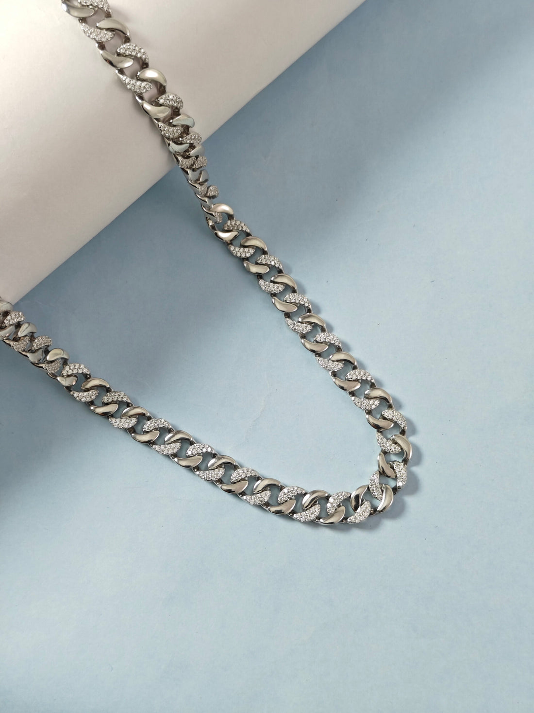 Silver chain necklace on a light blue background