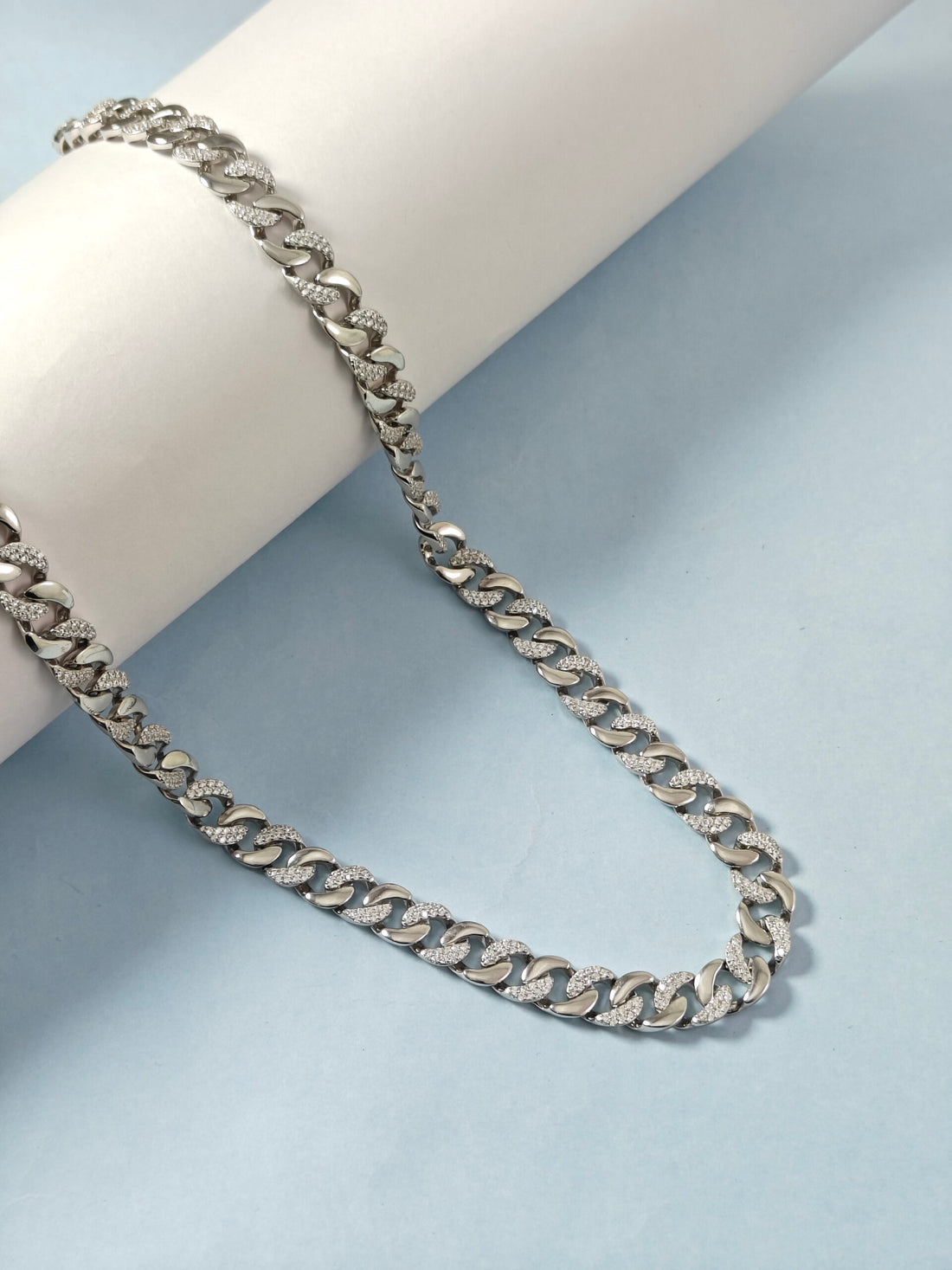Silver chain necklace on a light blue background