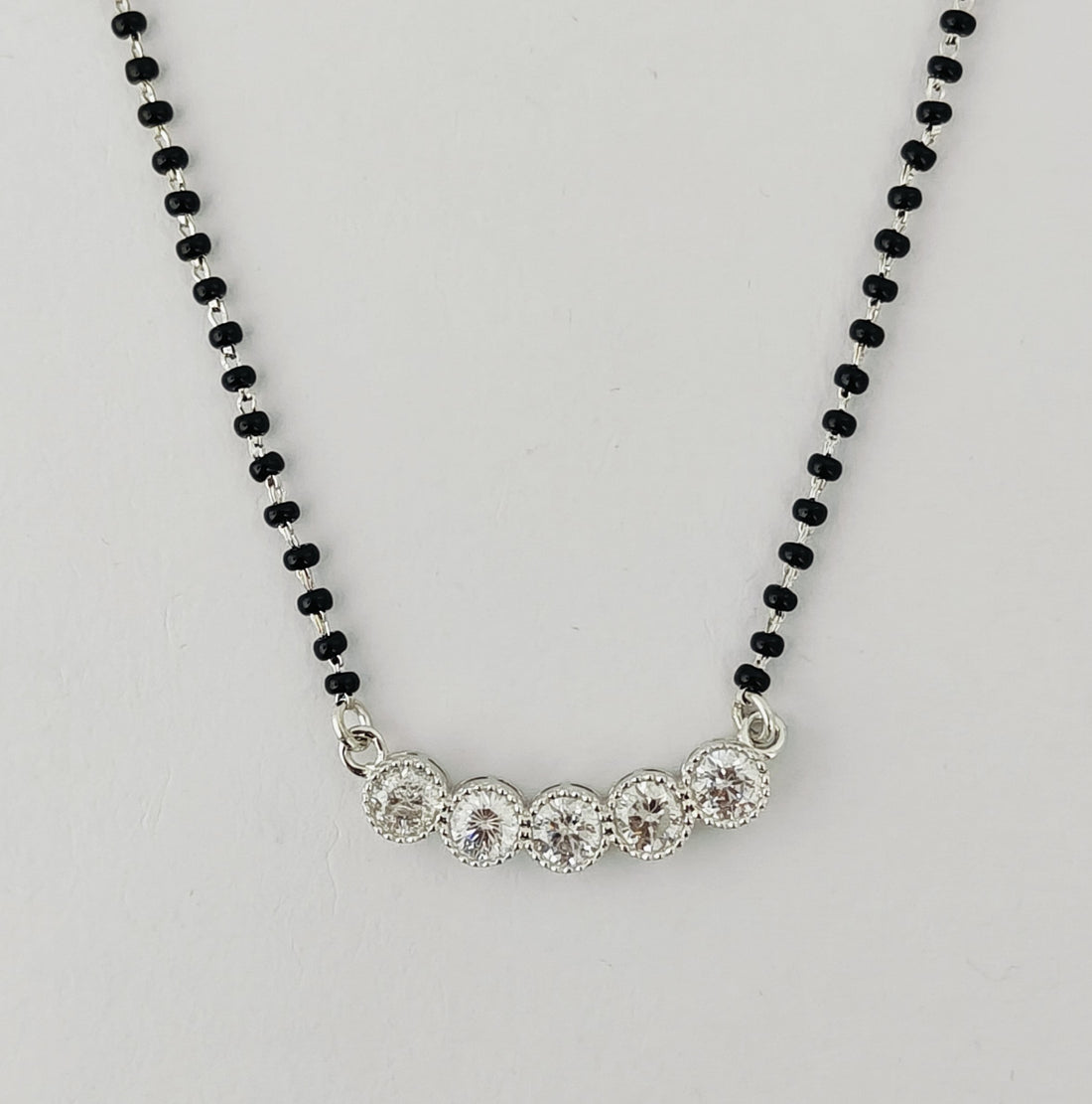 Necklace with black beaded chain and silver clasp on a light gray background