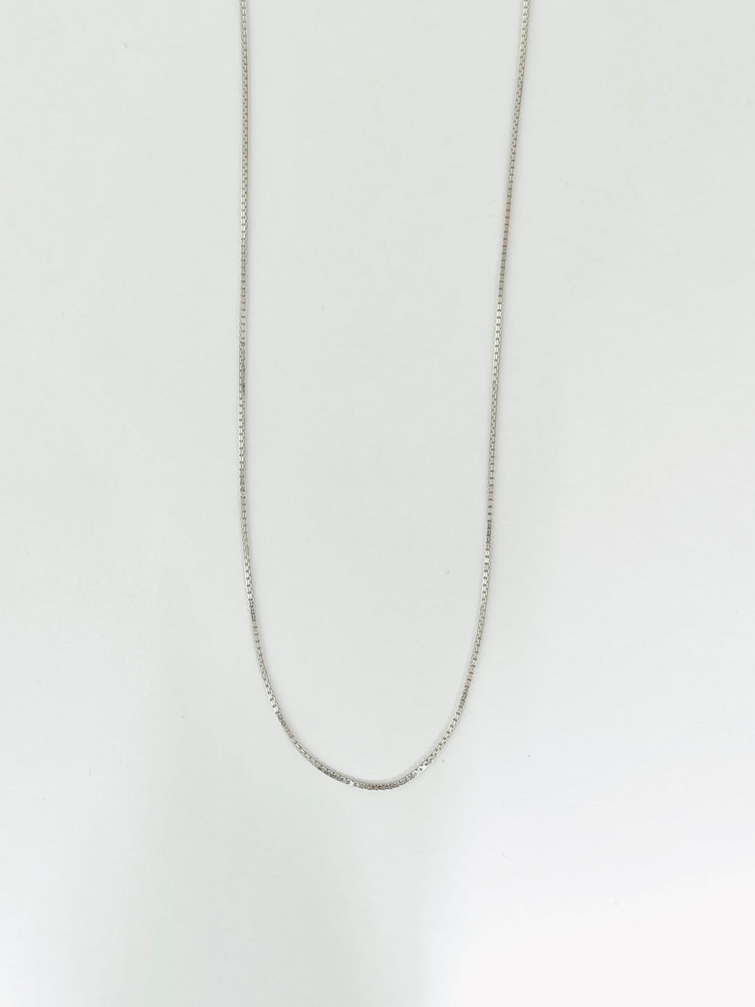 Silver chain necklace on a light gray background