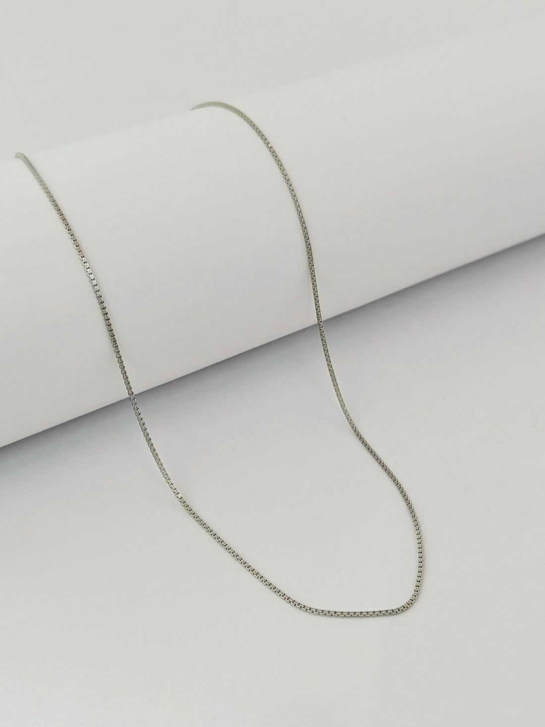Silver chain necklace on a light gray background