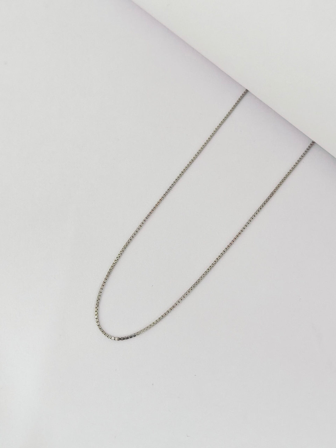 Silver chain necklace on a light gray background