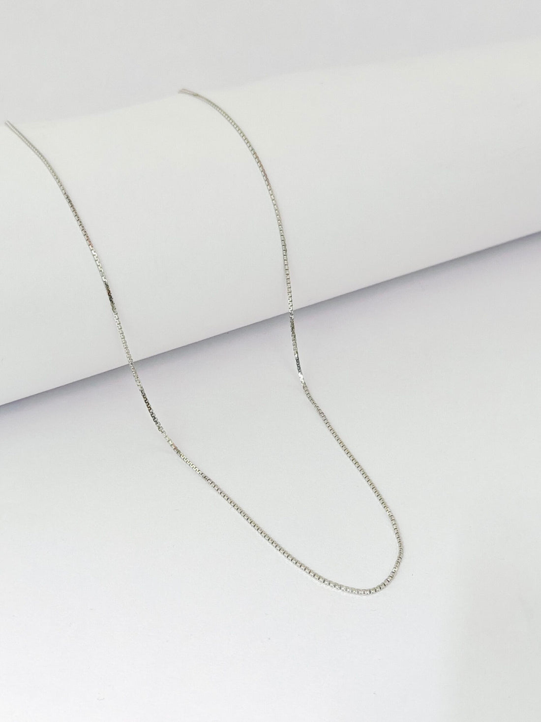 Silver chain necklace on a light gray background