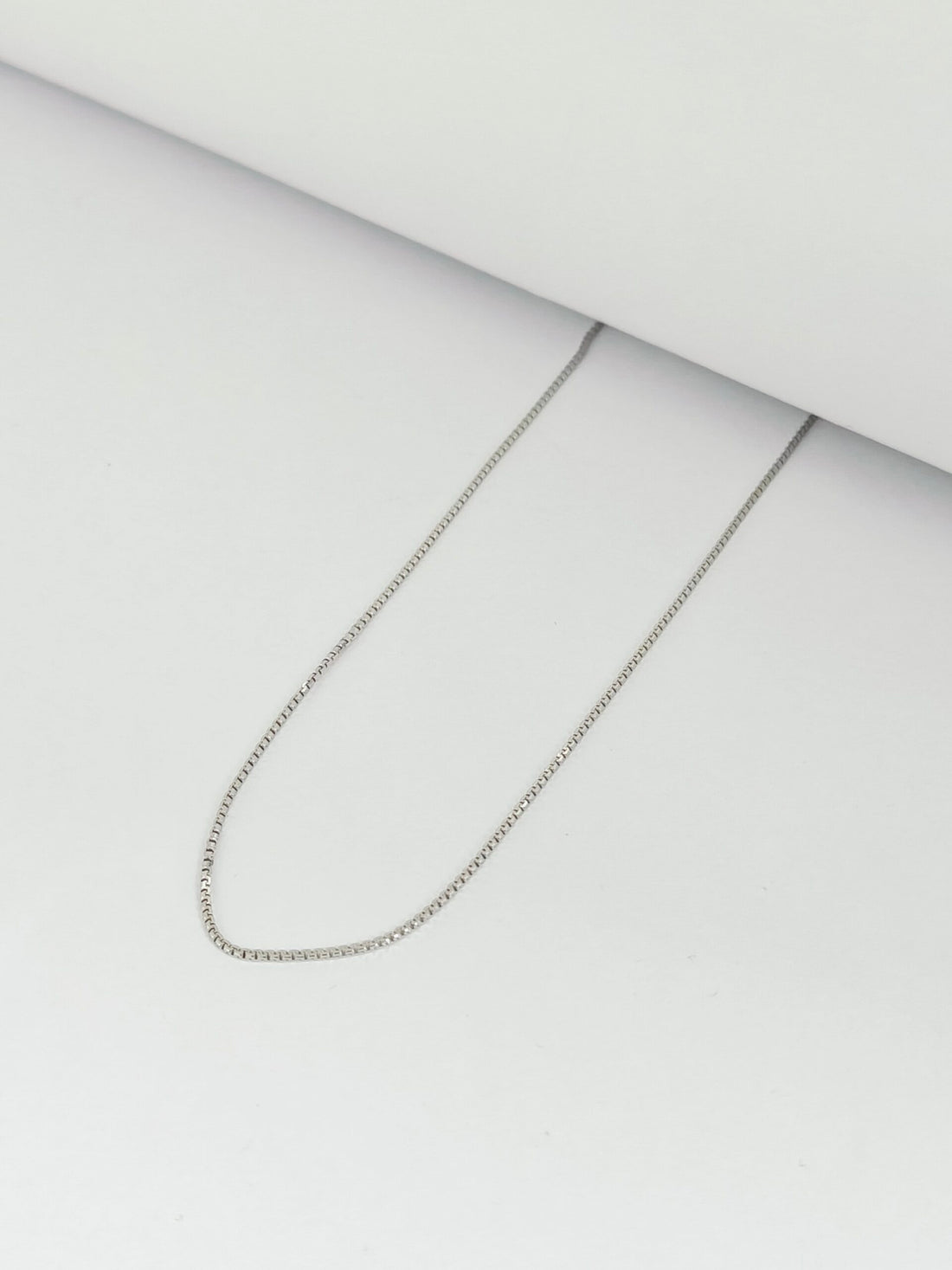 Silver chain necklace on a light gray background