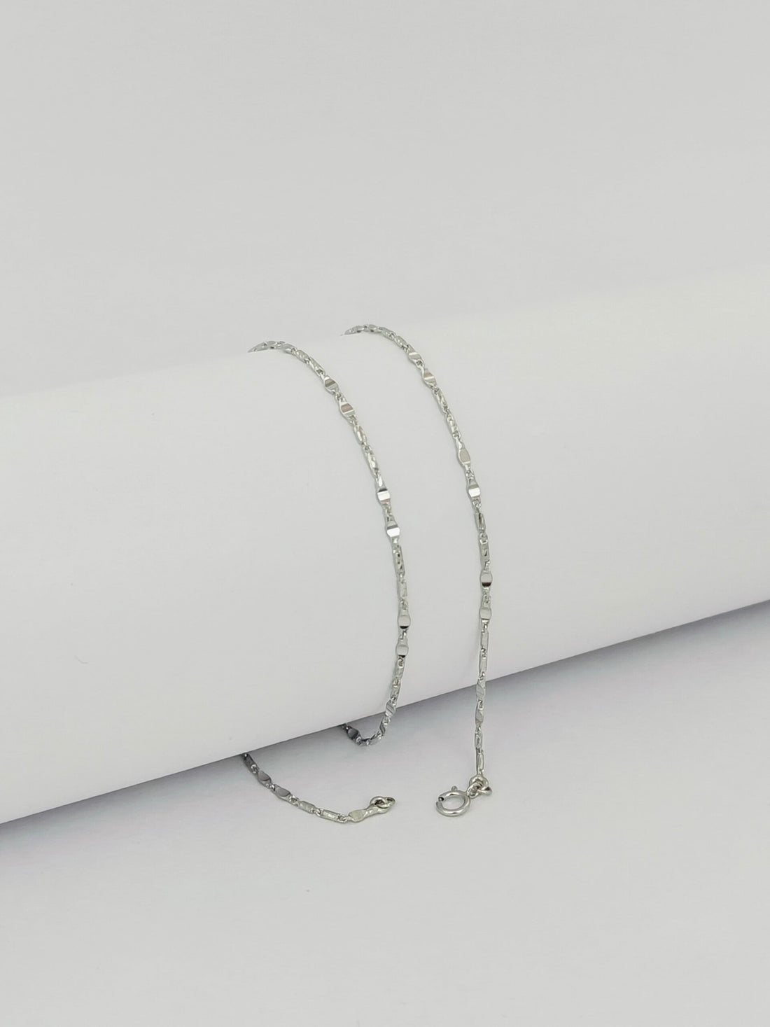 Silver chain necklace on a light gray background