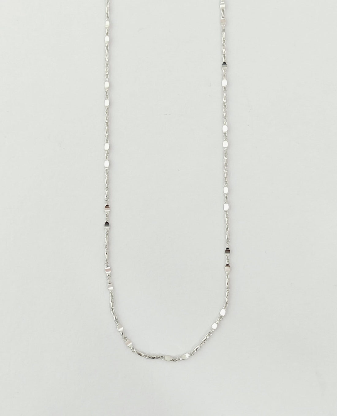 Silver chain necklace on a light gray background