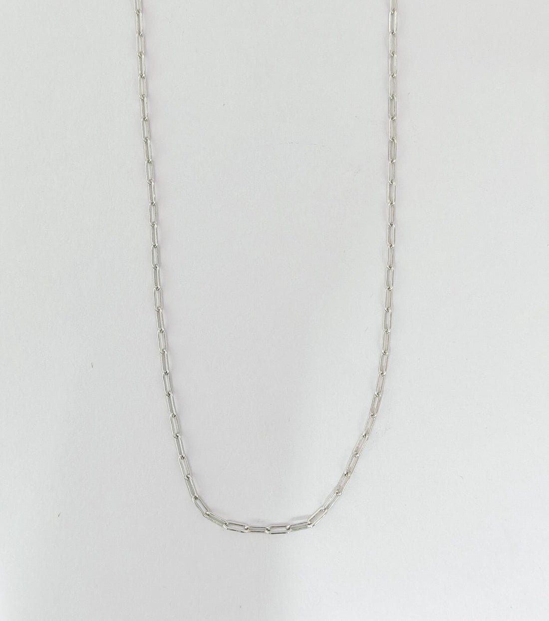 Silver chain necklace on a light gray background