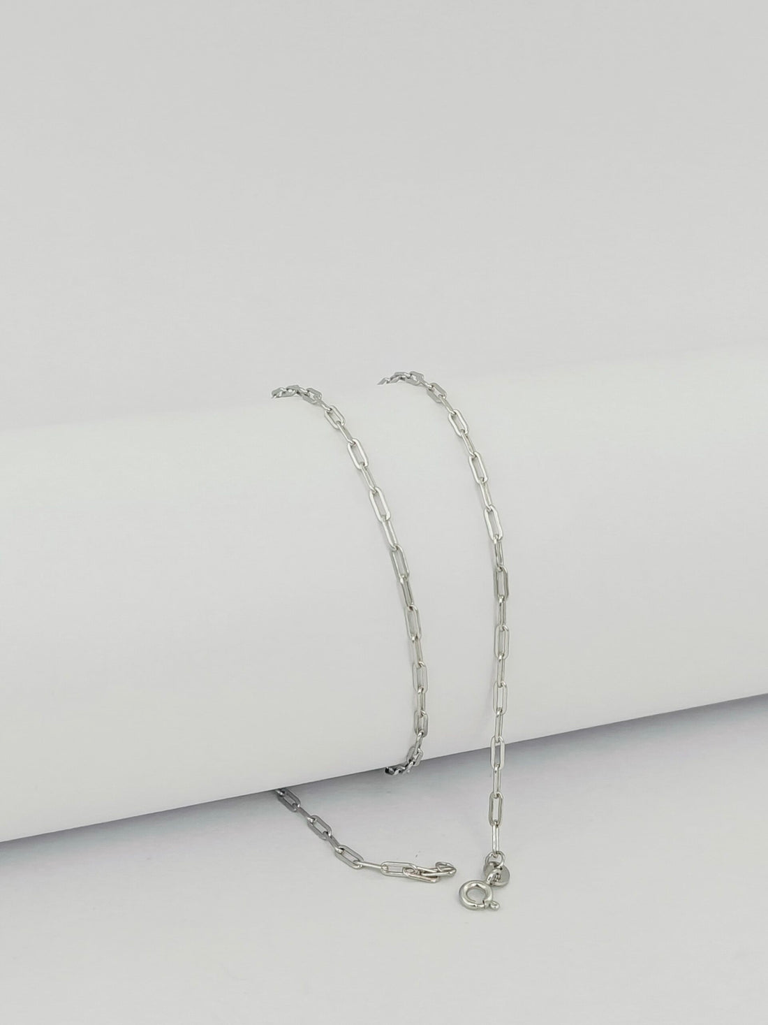 Silver chain necklace on a light gray background