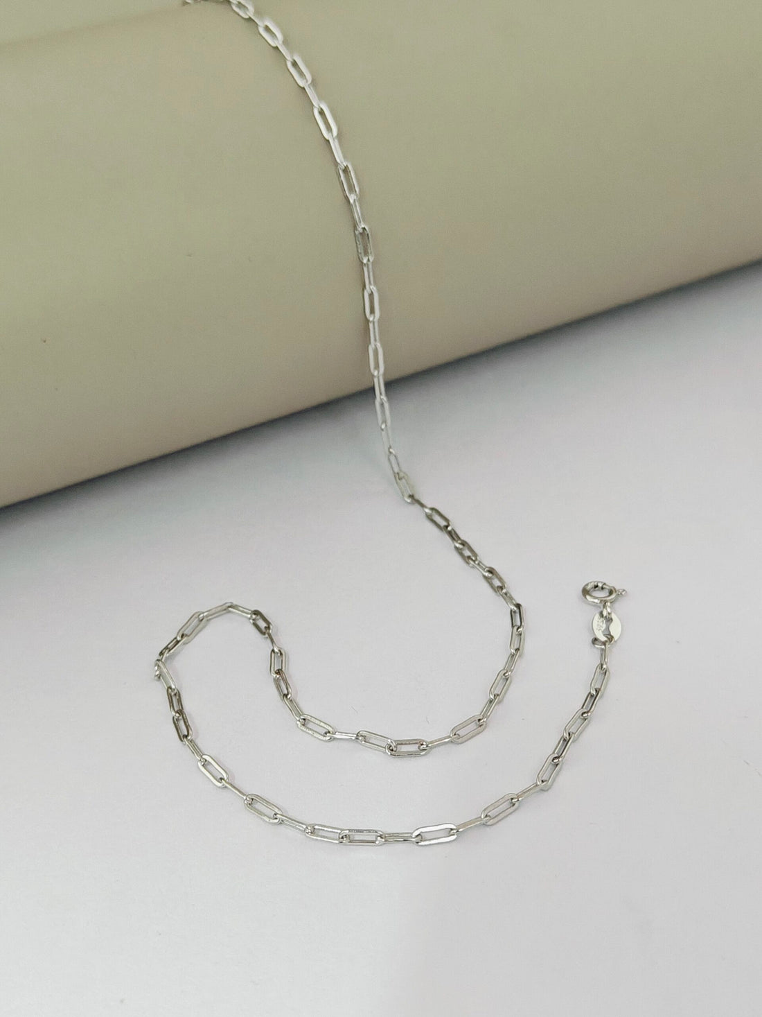 Silver chain necklace on a light gray surface