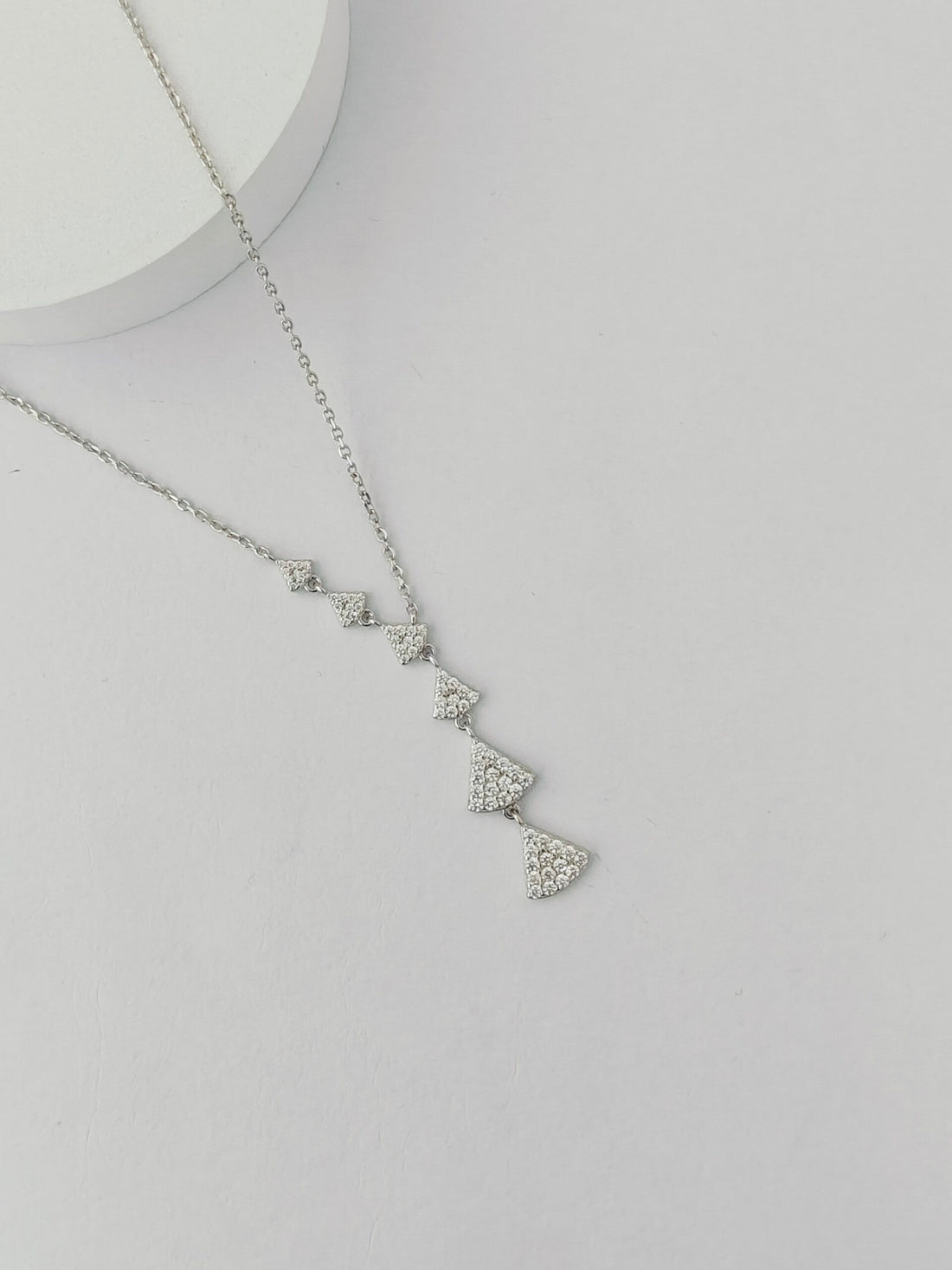 Silver necklace with heart-shaped pendant on a light gray background