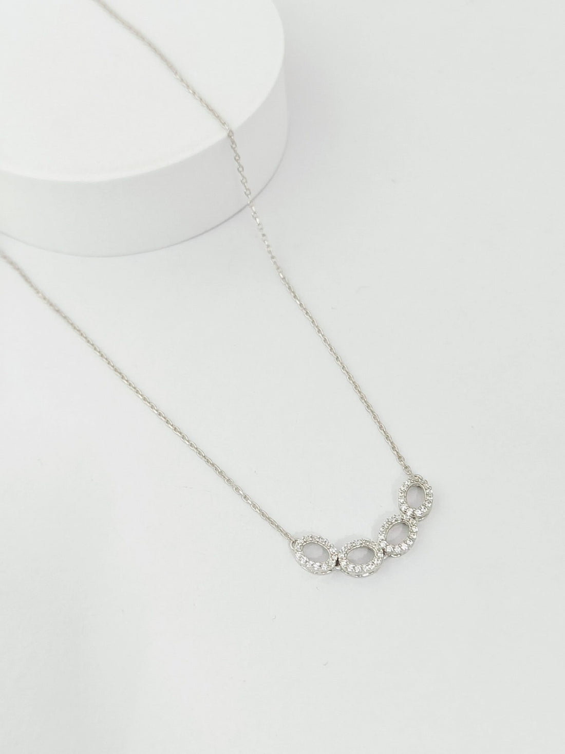 Silver necklace with circular pendants on a white background
