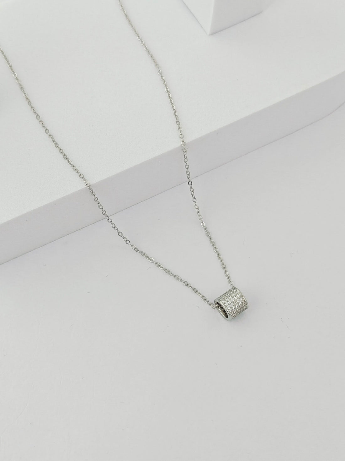 Silver necklace with a small pendant on a light gray background