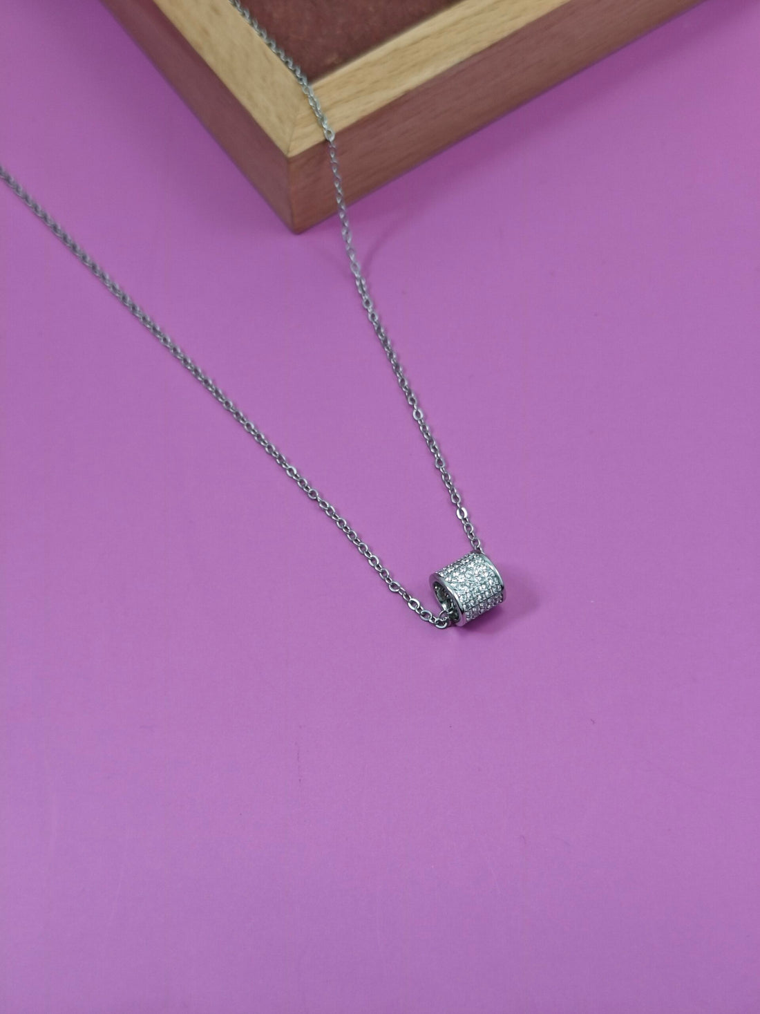 Silver necklace with a pendant on a pink background