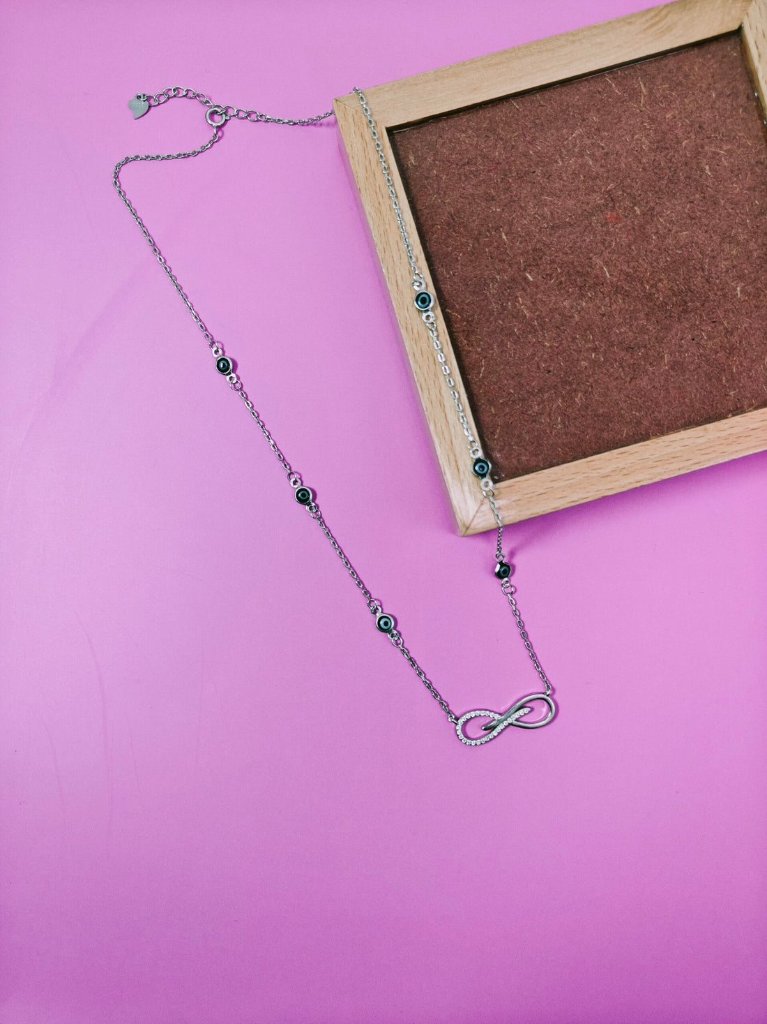 Necklace with an infinity symbol pendant on a pink background