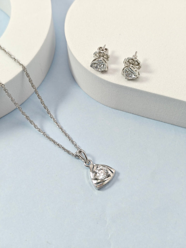 Silver necklace with heart-shaped pendant and matching earrings on a light blue background