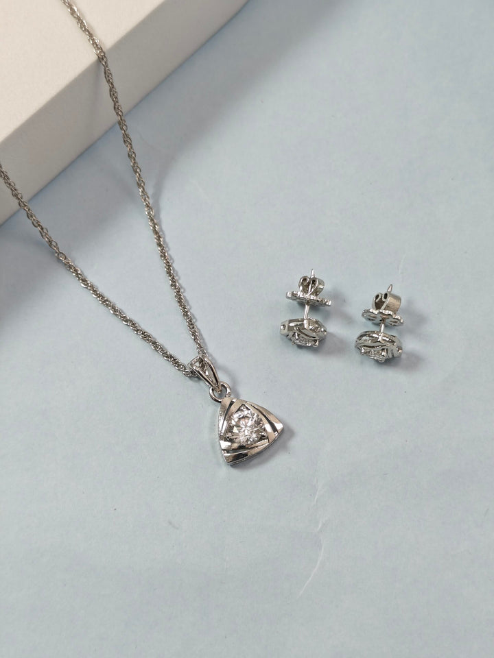 Silver necklace and earrings on a light gray surface