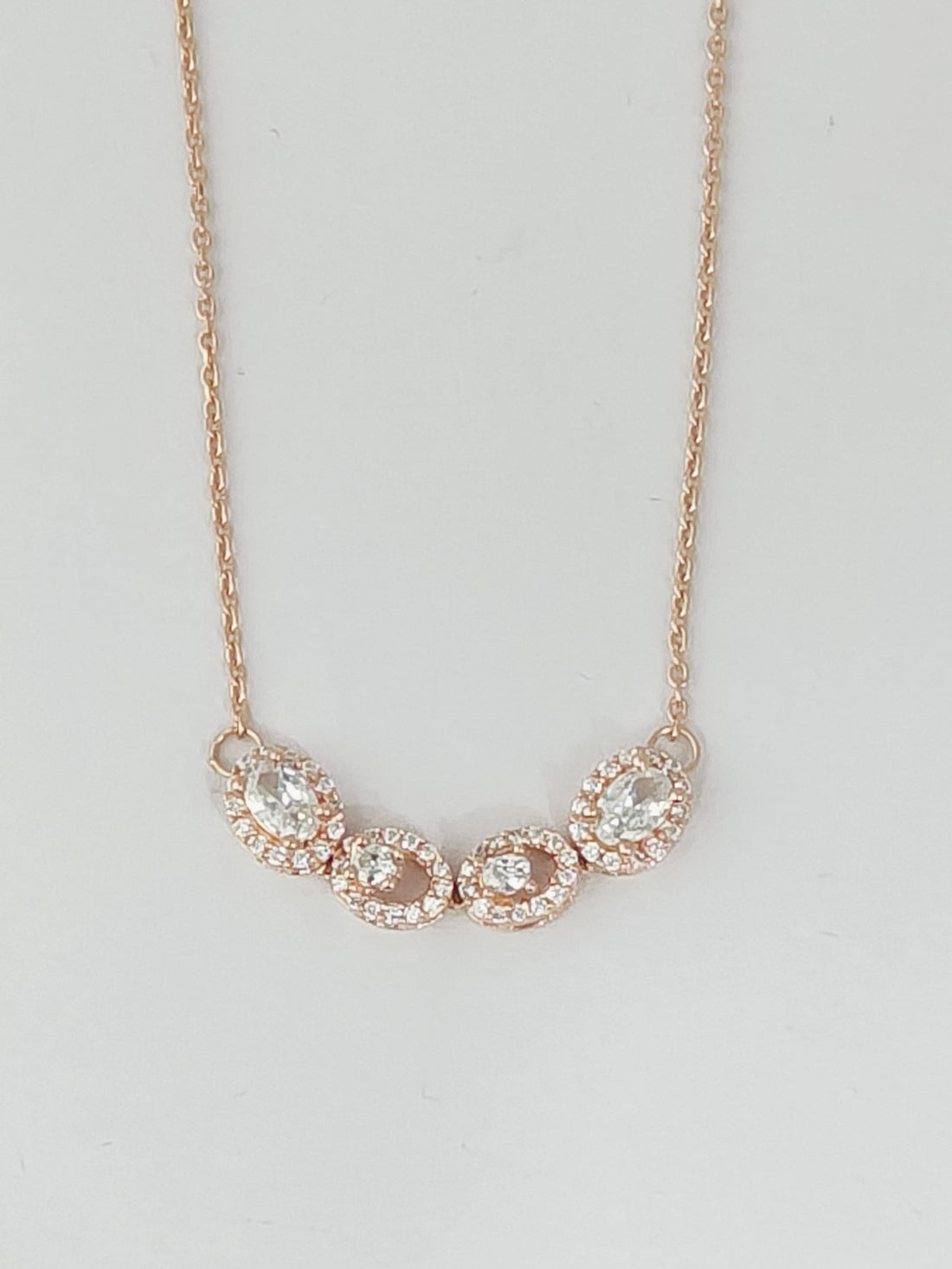 Rose gold necklace with clear stones on a light gray background