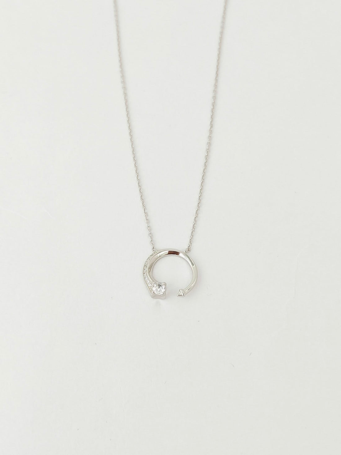 Silver necklace with a small pendant on a light gray background
