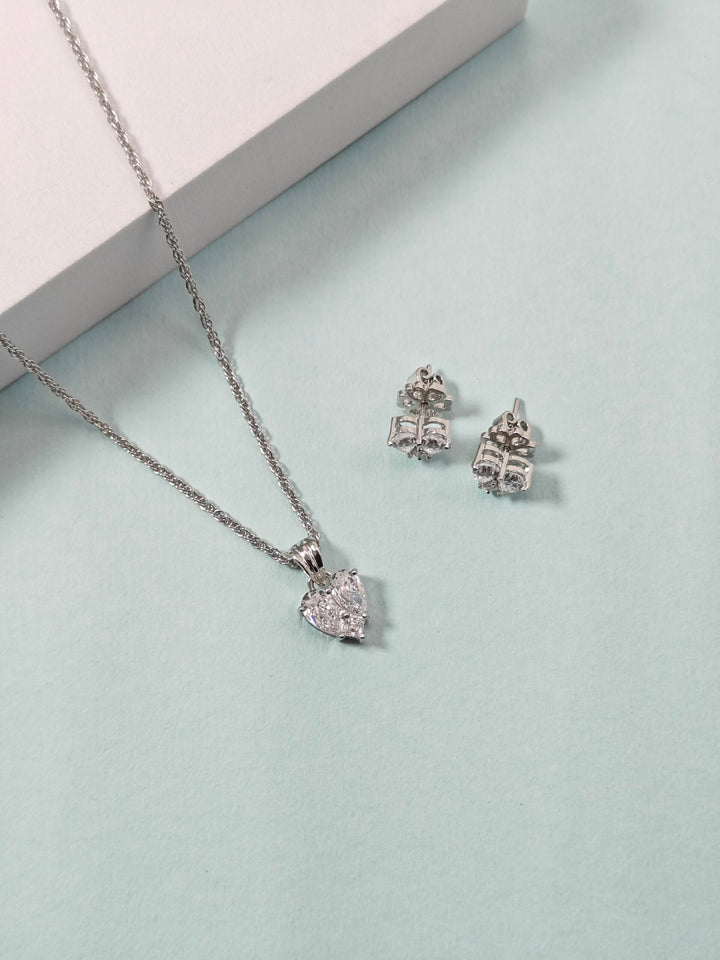 Silver necklace and earrings on a light blue surface