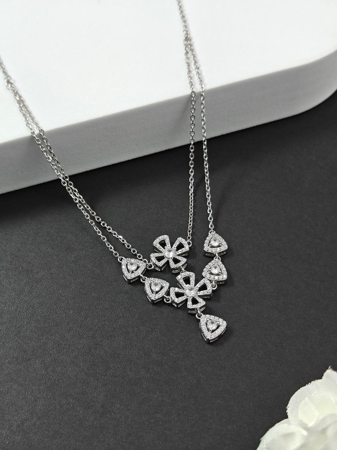 Silver necklace with heart-shaped pendants on a dark surface