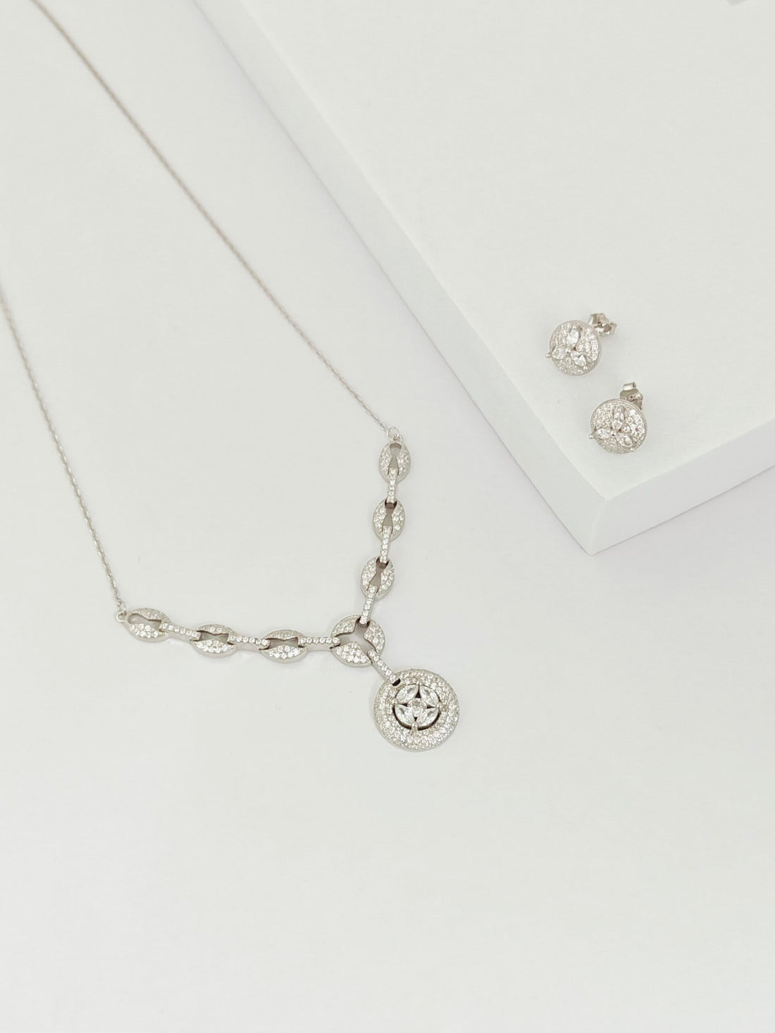 Silver necklace and earrings on a white background