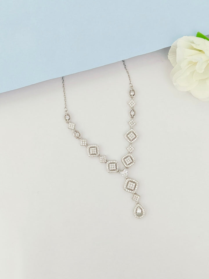 Silver necklace on a mannequin with a white flower background