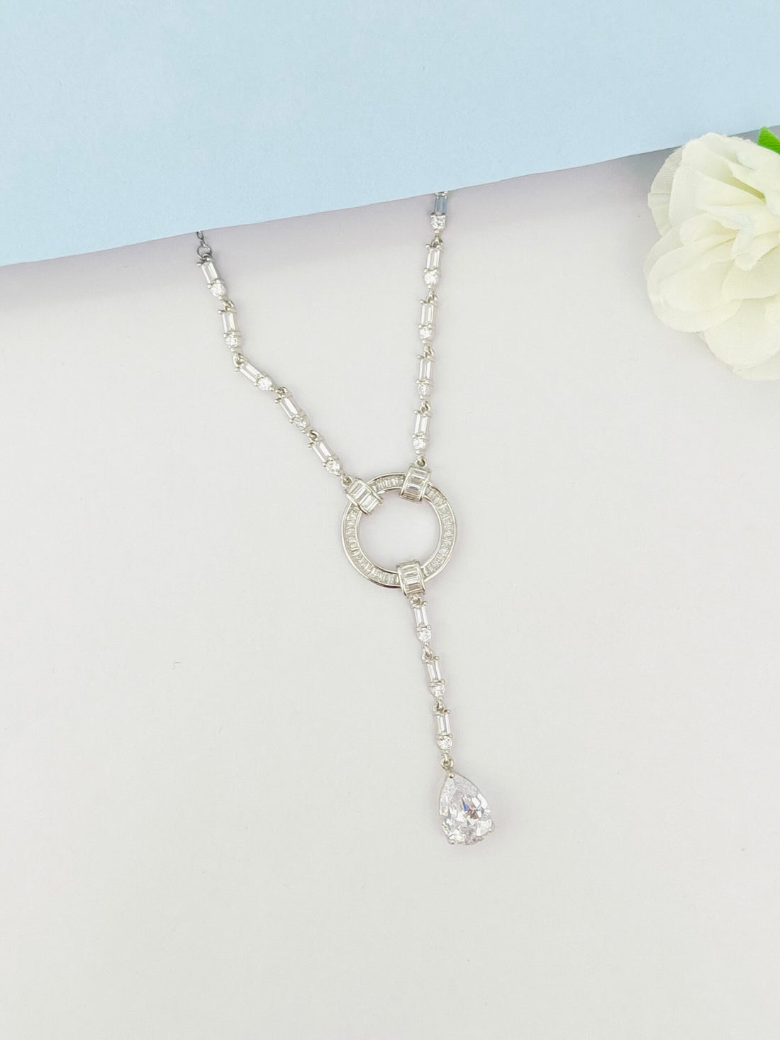 Silver necklace with a key pendant on a mannequin against a light blue background