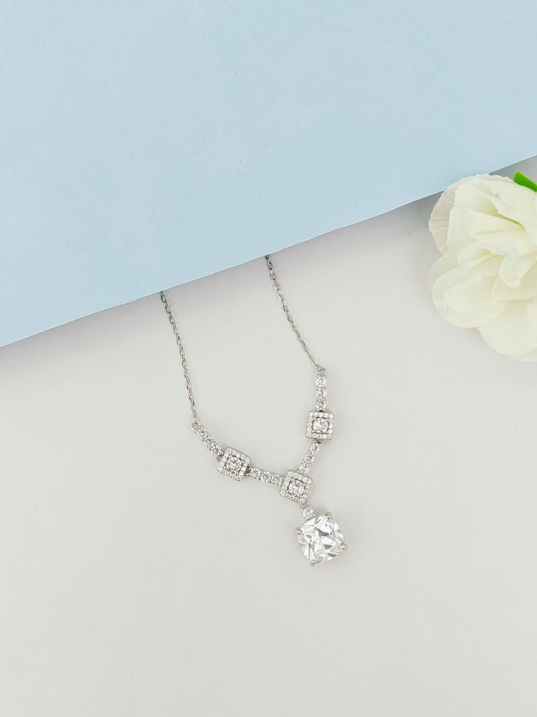 Silver necklace with a pendant on a mannequin bust against a light blue background