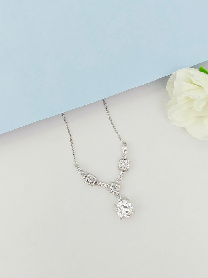 Silver necklace with a pendant on a mannequin bust against a light blue background