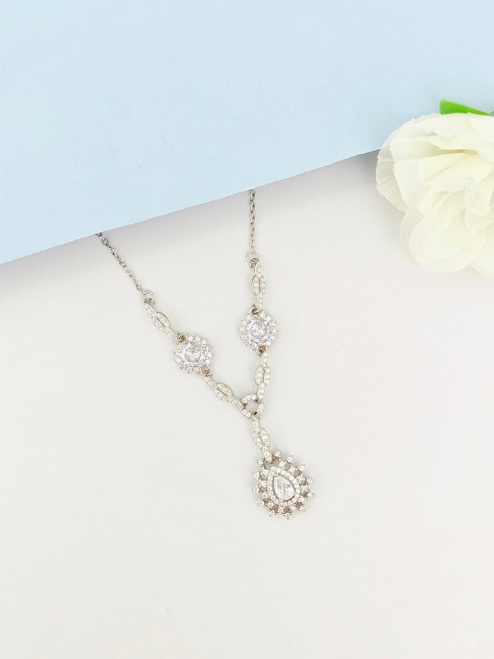 Silver necklace with floral elements on a mannequin bust against a light blue background