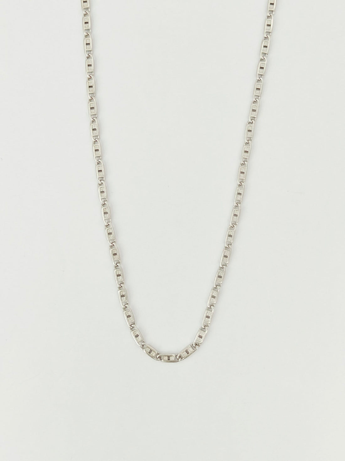 Silver chain necklace on a light gray background
